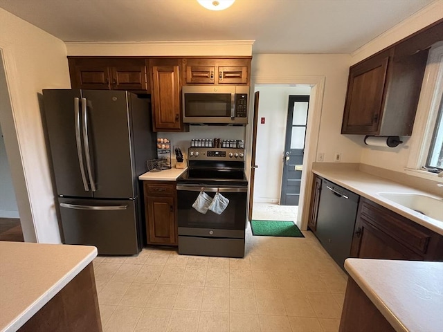 kitchen with stainless steel appliances, a sink, light countertops, and dark brown cabinetry