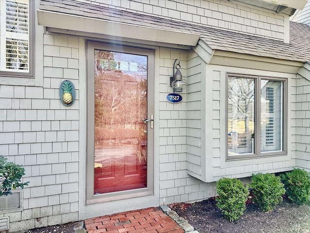 doorway to property featuring roof with shingles