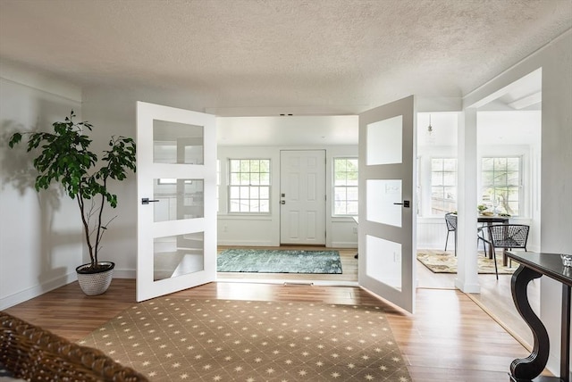 entrance foyer with wood-type flooring, a textured ceiling, and french doors