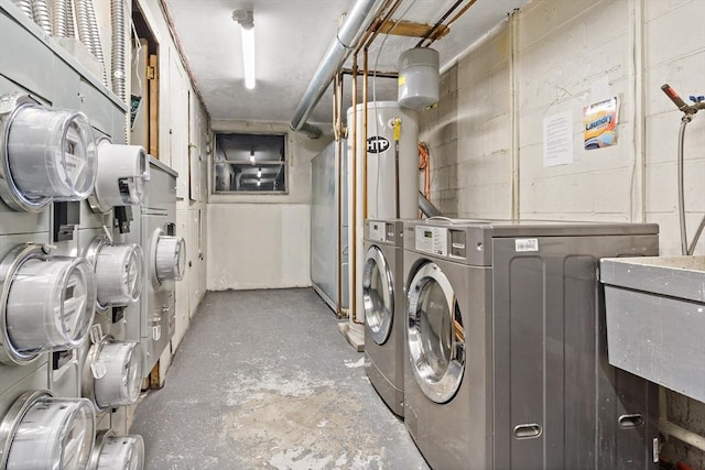 washroom featuring concrete block wall, water heater, and independent washer and dryer