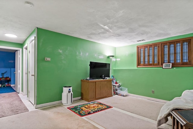 living area with a textured ceiling, carpet flooring, visible vents, and baseboards