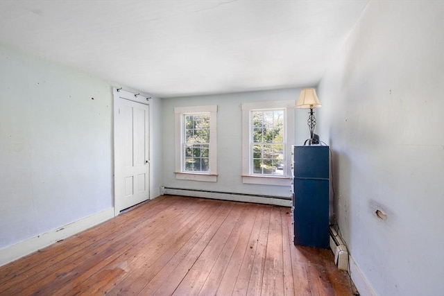 unfurnished bedroom with a baseboard radiator, wood-type flooring, and baseboards
