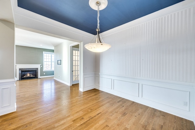 unfurnished dining area featuring a premium fireplace and light hardwood / wood-style flooring