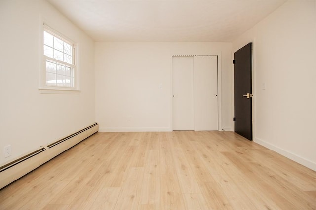 unfurnished room with light hardwood / wood-style floors and baseboard heating