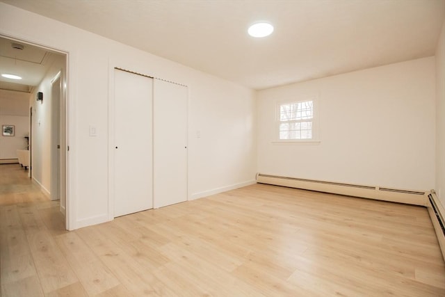 unfurnished bedroom featuring a baseboard radiator, light wood-type flooring, and a closet