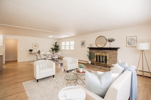 living room featuring baseboard heating, a fireplace, and light hardwood / wood-style flooring