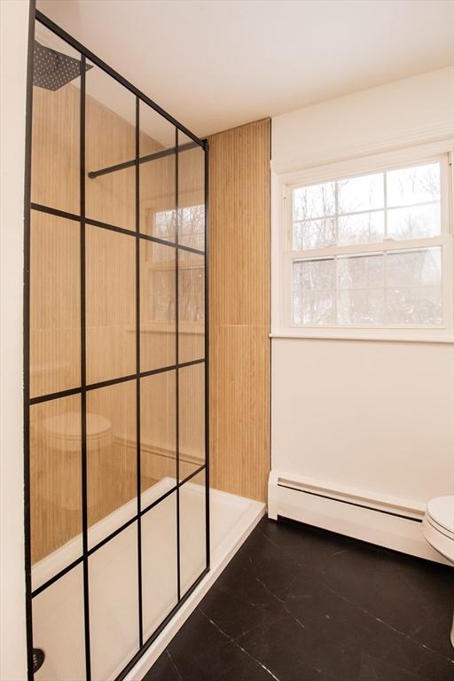 bathroom featuring a shower, baseboard heating, and toilet