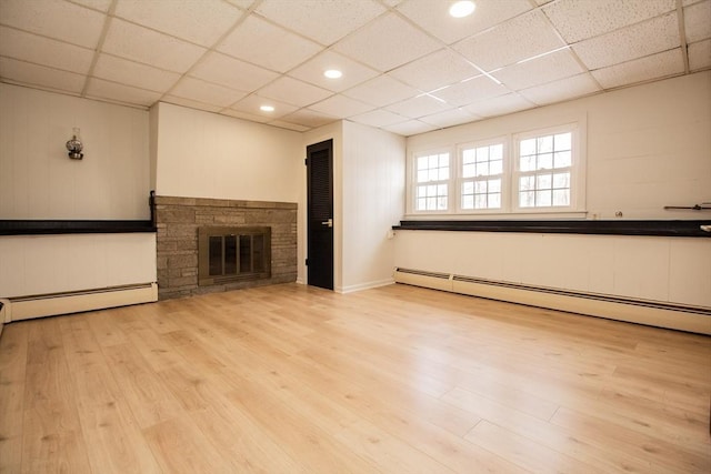 unfurnished living room with a fireplace, a paneled ceiling, light hardwood / wood-style floors, and baseboard heating