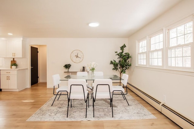 dining space with a baseboard radiator and light hardwood / wood-style floors