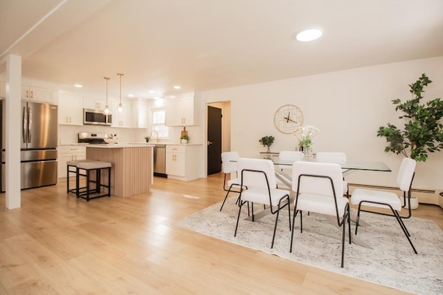 dining space with sink and light hardwood / wood-style flooring