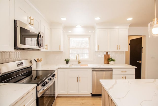 kitchen featuring appliances with stainless steel finishes, sink, white cabinets, hanging light fixtures, and light stone countertops