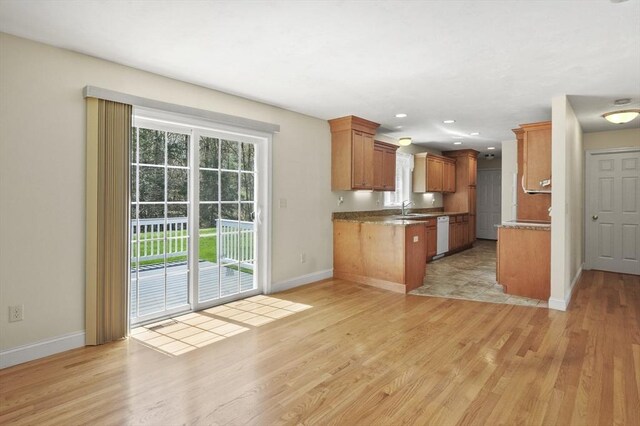 kitchen featuring baseboards, light wood-style flooring, and a sink
