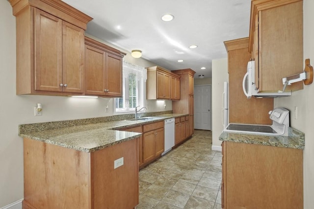 kitchen featuring baseboards, white appliances, a sink, a peninsula, and brown cabinets