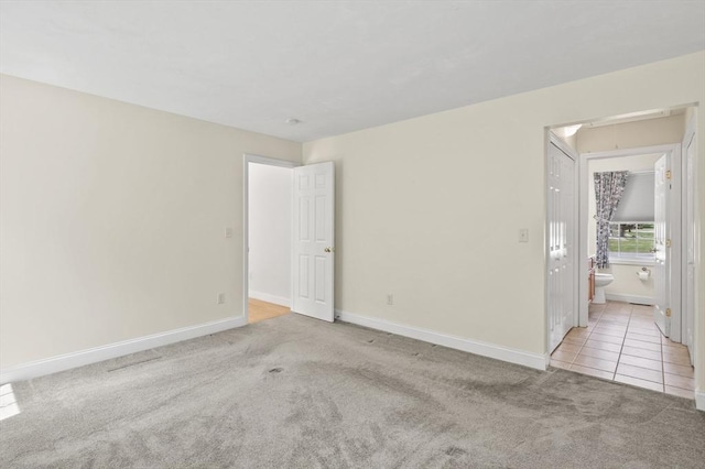 empty room featuring baseboards, tile patterned flooring, and carpet