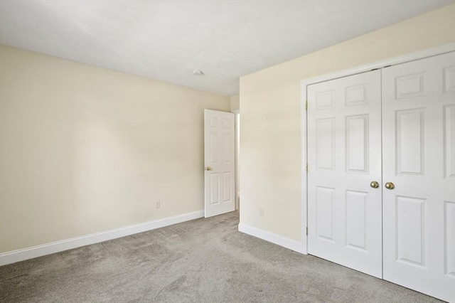 unfurnished bedroom with baseboards, carpet flooring, and a closet