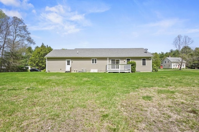 back of property featuring a deck and a lawn