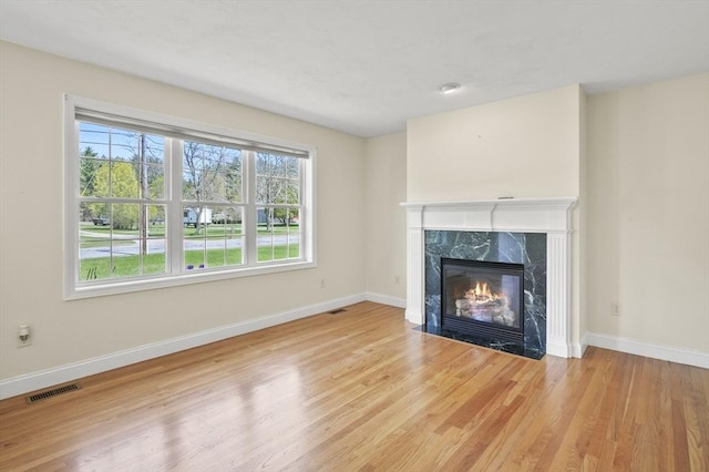 unfurnished living room featuring a fireplace, baseboards, visible vents, and wood finished floors