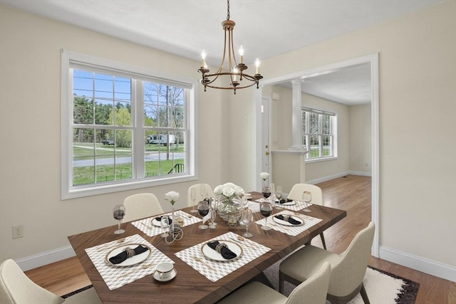 dining area with a chandelier, baseboards, ornate columns, and wood finished floors