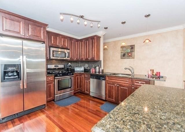 255 Winter St Unit 305, Waltham, MA 02451 - kitchen featuring appliances with stainless steel finishes, dark wood finished floors, dark stone countertops, decorative backsplash, and ornamental molding