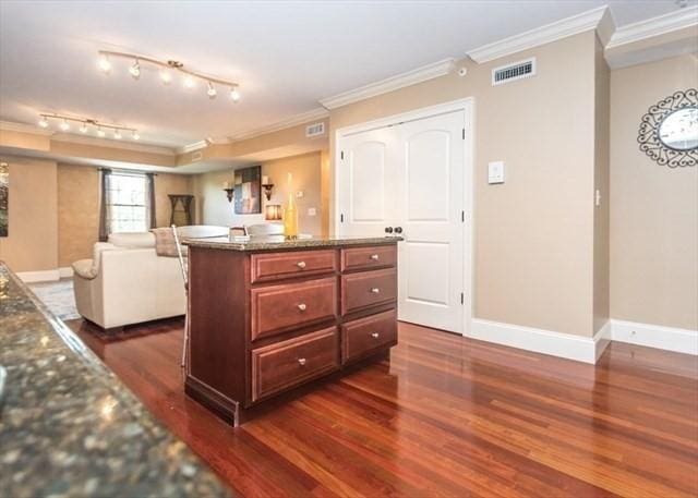 255 Winter St Unit 305, Waltham, MA 02451 - kitchen with crown molding, dark wood-type flooring, open floor plan, a center island, and dark stone countertops