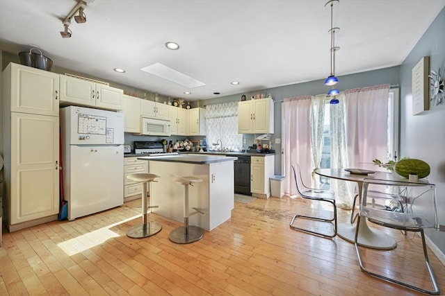 1249-1251 Rockdale Ave, New Bedford, MA 02740 - kitchen featuring white appliances, a skylight, a center island, a sink, and dark countertops