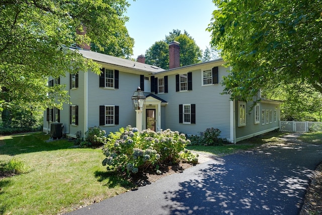 colonial-style house featuring central AC unit and a front yard