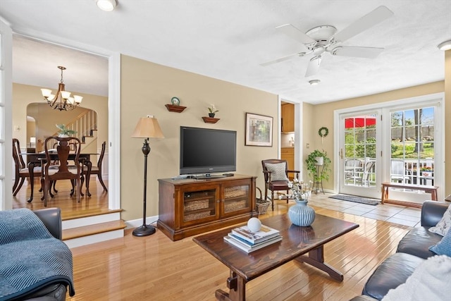 living area featuring baseboards, ceiling fan with notable chandelier, and light wood-style flooring