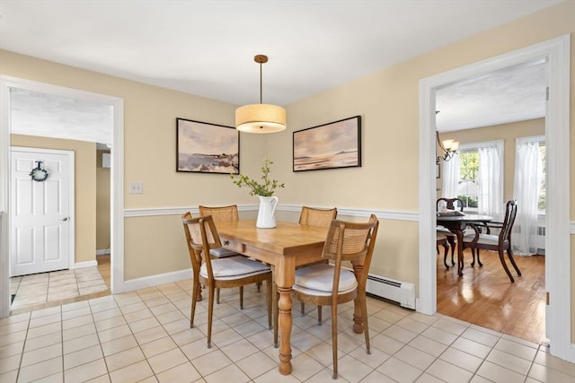 dining space featuring an inviting chandelier, baseboards, a baseboard heating unit, and light tile patterned flooring