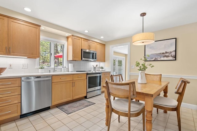 kitchen with light countertops, a sink, tasteful backsplash, and stainless steel appliances