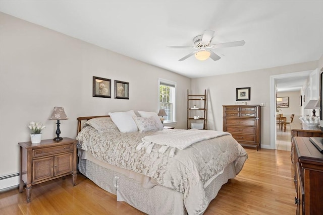 bedroom with a ceiling fan, a baseboard heating unit, and light wood-style floors