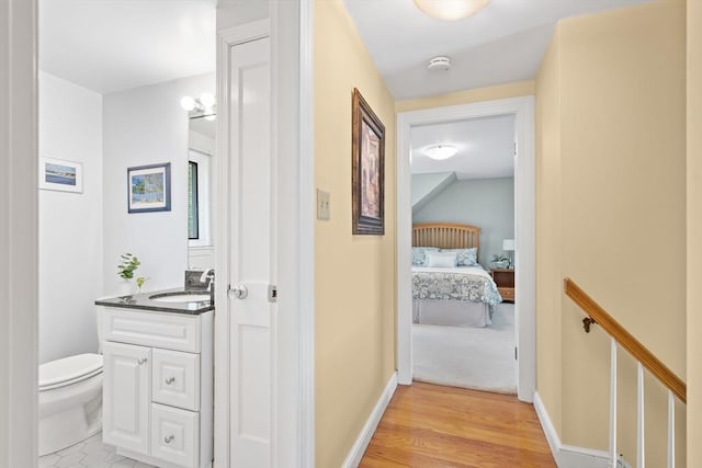 hall with a sink, baseboards, and light wood-type flooring