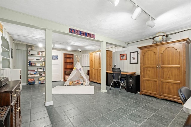 finished basement featuring dark tile patterned floors and rail lighting