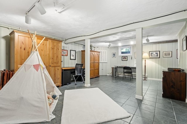 below grade area featuring track lighting, baseboards, and dark tile patterned flooring