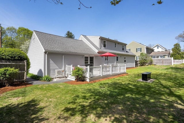back of house with fence, a wooden deck, a shingled roof, and a yard