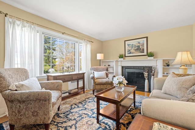 living area with a fireplace with flush hearth, wood finished floors, and radiator