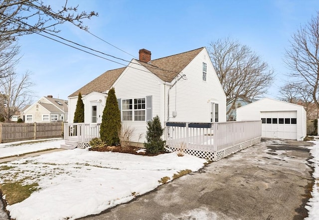 view of snow covered exterior with an outbuilding, a garage, and a deck