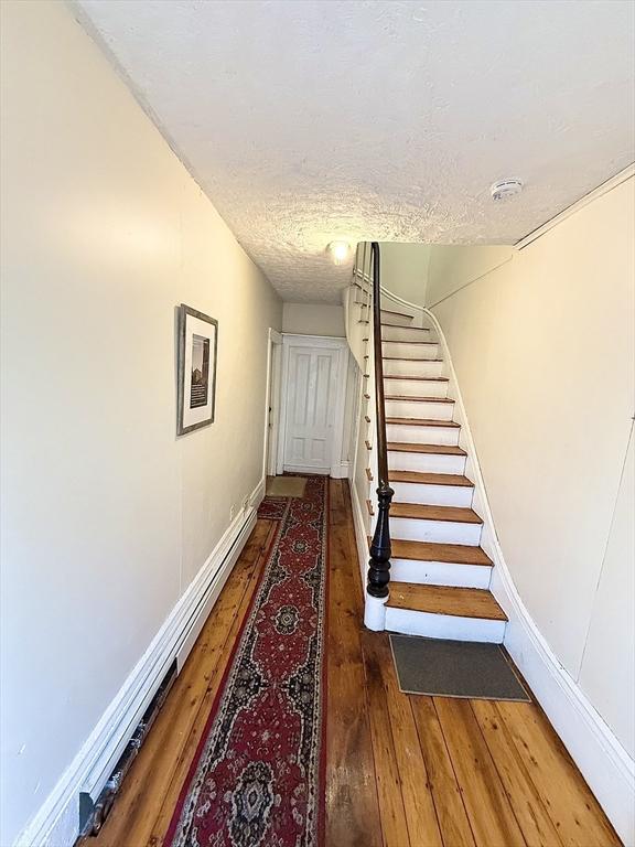 staircase with hardwood / wood-style floors and a textured ceiling