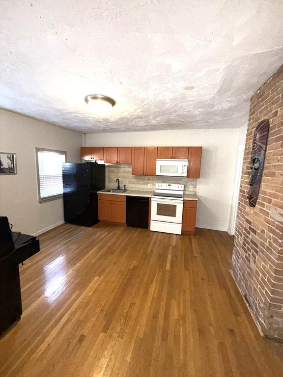 kitchen featuring decorative backsplash, sink, black appliances, and hardwood / wood-style flooring