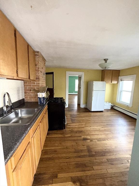 kitchen with dark hardwood / wood-style floors, white fridge, baseboard heating, and sink