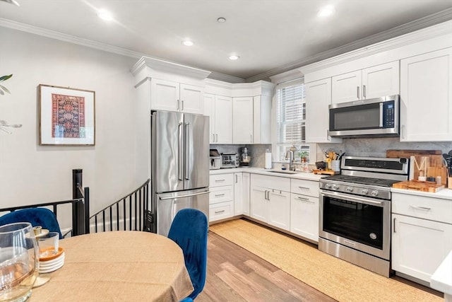 23 Dix St Unit 1, Boston, MA 02122 - kitchen featuring stainless steel appliances, a sink, light wood-type flooring, ornamental molding, and tasteful backsplash