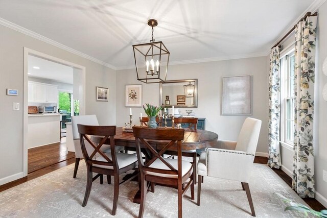 dining room with wood finished floors, ornamental molding, a chandelier, and baseboards