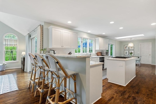 kitchen featuring a kitchen island, white cabinets, healthy amount of natural light, dark wood-type flooring, and recessed lighting