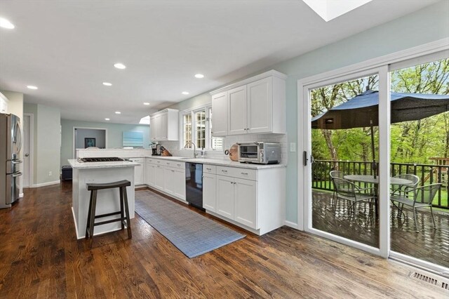 kitchen with black dishwasher, freestanding refrigerator, backsplash, light countertops, and dark wood-type flooring
