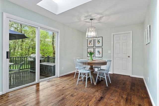 dining area with a skylight, wood finished floors, and baseboards