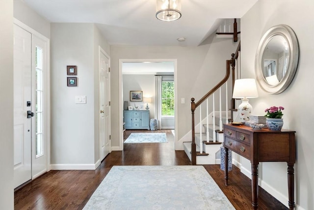 entryway with dark wood-style floors, stairs, and baseboards
