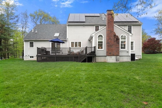 rear view of property with a deck, a yard, and a chimney