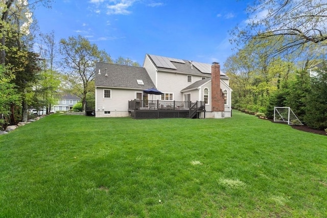 rear view of property featuring a deck, a lawn, a chimney, and a gazebo