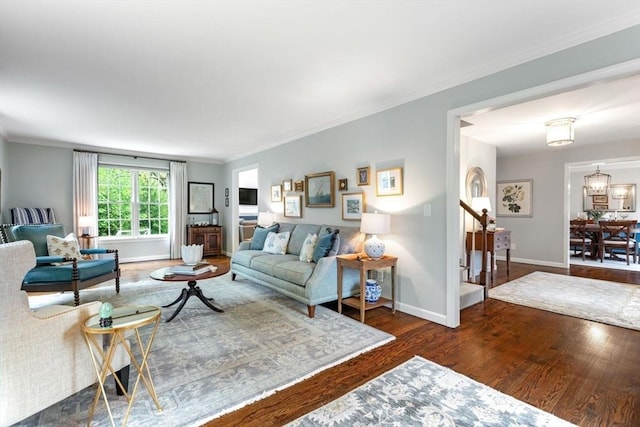 living area featuring wood finished floors, baseboards, ornamental molding, and stairway