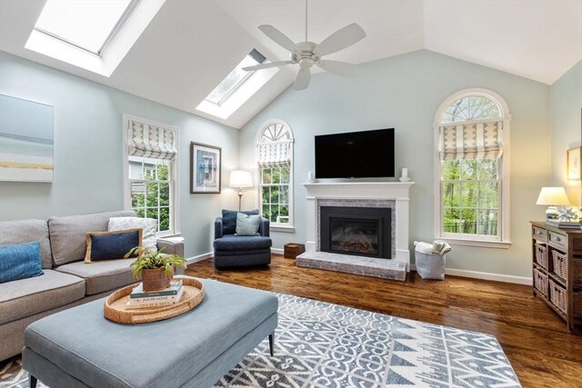 living area featuring a skylight, healthy amount of natural light, vaulted ceiling, and wood finished floors