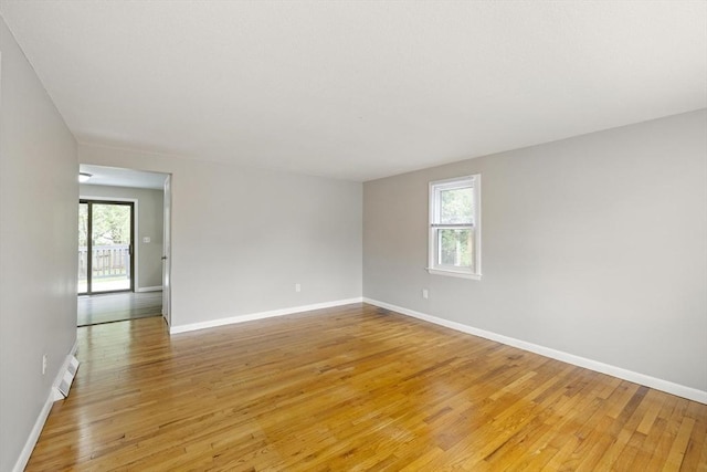 spare room featuring plenty of natural light, light wood finished floors, and baseboards
